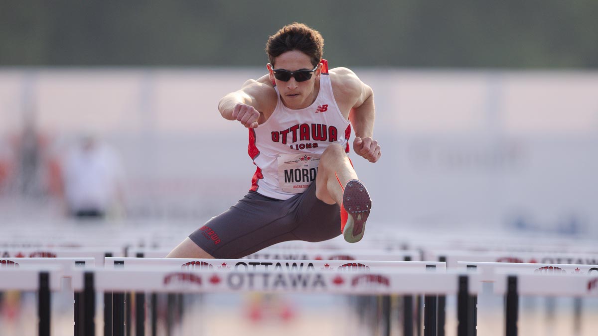 Teen athlete running over a hurdle